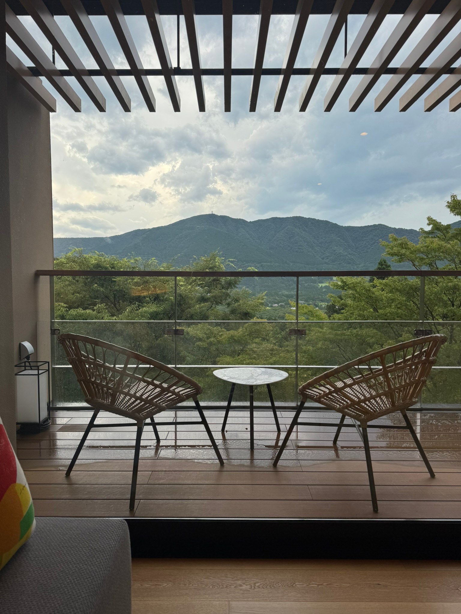 Timber pergola slats casting shade over two chairs, with mountains beyond, at a ryokan in Hakone